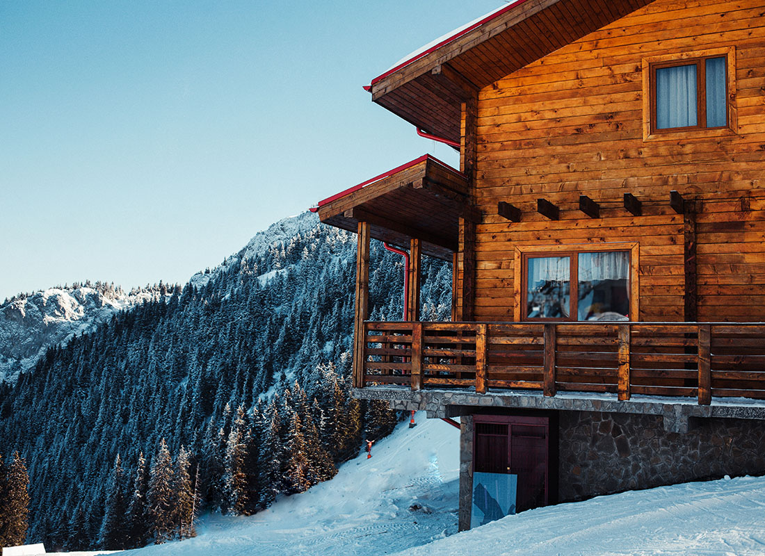 Contact - Wooden Ski Resort Building Exterior with Views of Snow Covered Trees and Mountains Against a Clear Blue Sky