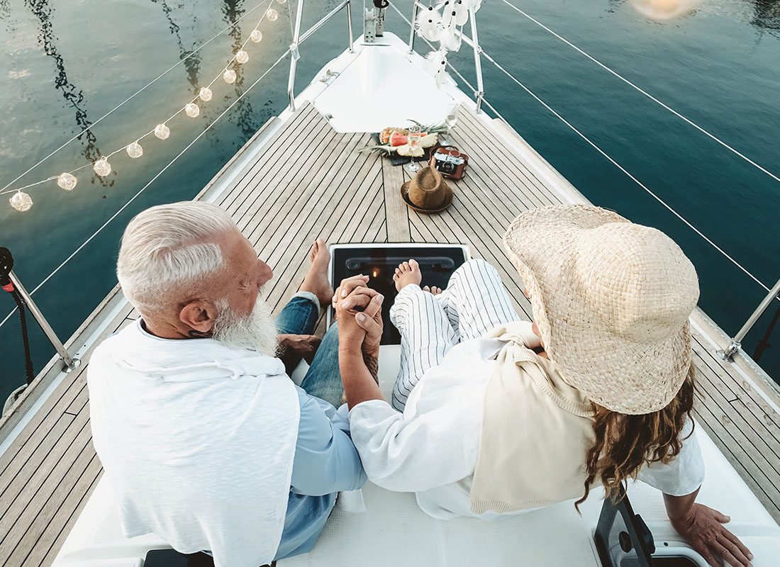 Employee Benefits - Rear View of a Wealthy Mature Couple Sitting on a Romantic Boat on the Ocean During a Vacation