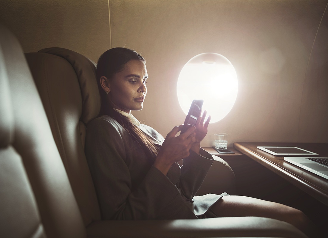 Insurance Solutions - Portrait of a Business Woman Using Her Phone While She Sits on a Private Jet During a Work Trip