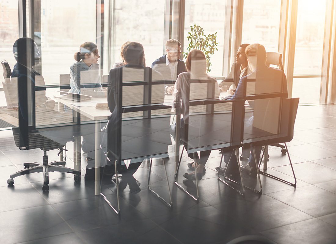 Meet Our Team - View Through the Glass of Business People Sitting Around a Conference Table During a Meeting in the Office