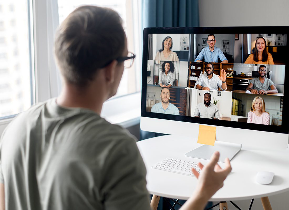 Recorded Webinars from Cambridge - Man Looking at Computer During Webinar with Multiple People on the Screen Watching